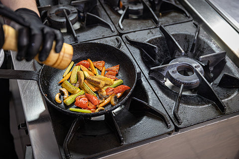 Frying pan with vegetables on a gas stove